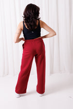 Kobieta w bordowych spodniach BalticBird, dopasowany pas z troczkiem, luźny fason, wygodne kieszenie boczne.