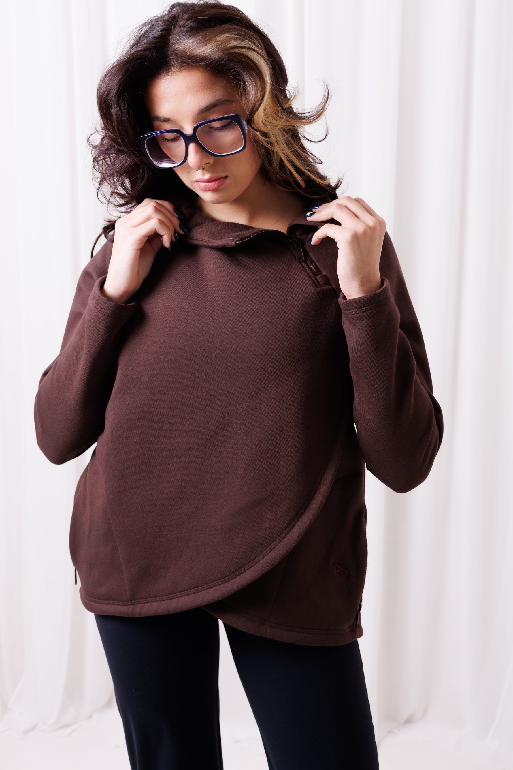 Modelka w brązowej bluzie Papaya z asymetrycznym przodem i przedłużonym tyłem, uszytej ze 100%  polskiej bawełny. Bluza ma kieszenie z zamkami.  odzież sportowa damska szyta w Polsce, Gdańsk.