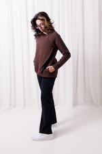 Modelka w brązowej bluzie Papaya z asymetrycznym przodem i przedłużonym tyłem, uszytej ze 100%  polskiej bawełny. Bluza ma kieszenie z zamkami.  odzież sportowa damska szyta w Polsce, Gdańsk.