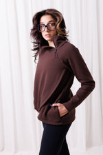Modelka w brązowej bluzie Papaya z asymetrycznym przodem i przedłużonym tyłem, uszytej ze 100%  polskiej bawełny. Bluza ma kieszenie z zamkami.  odzież sportowa damska szyta w Polsce, Gdańsk.