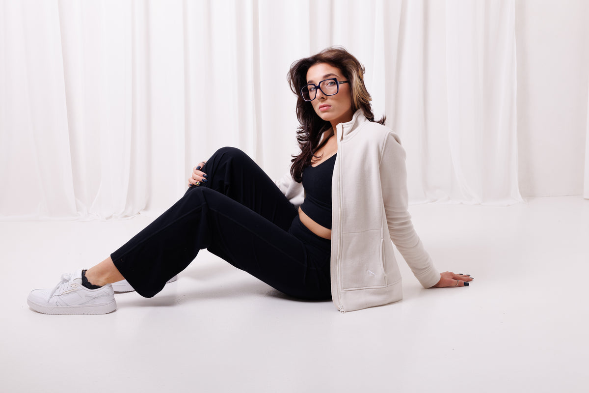 Modelka w jasnej bluzie BalticBird Straight ecru siedząca w minimalistycznym wnętrzu, wygodna bluza na co dzień.