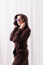 Modelka w długiej brązowej bluzie Long BalticBird z polskiej bawełny, zapinanej na suwak, z kieszeniami i wydłużonym tyłem;  w Gdańsku; odzież sportowa dla kobiet 30+ dopasowana do sylwetek jabłko, gruszka i kolumna.